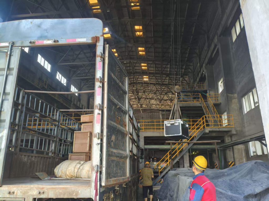On-site engineers unloading and hoisting measuring instrument crates for installation at a Malaysian chemical factory